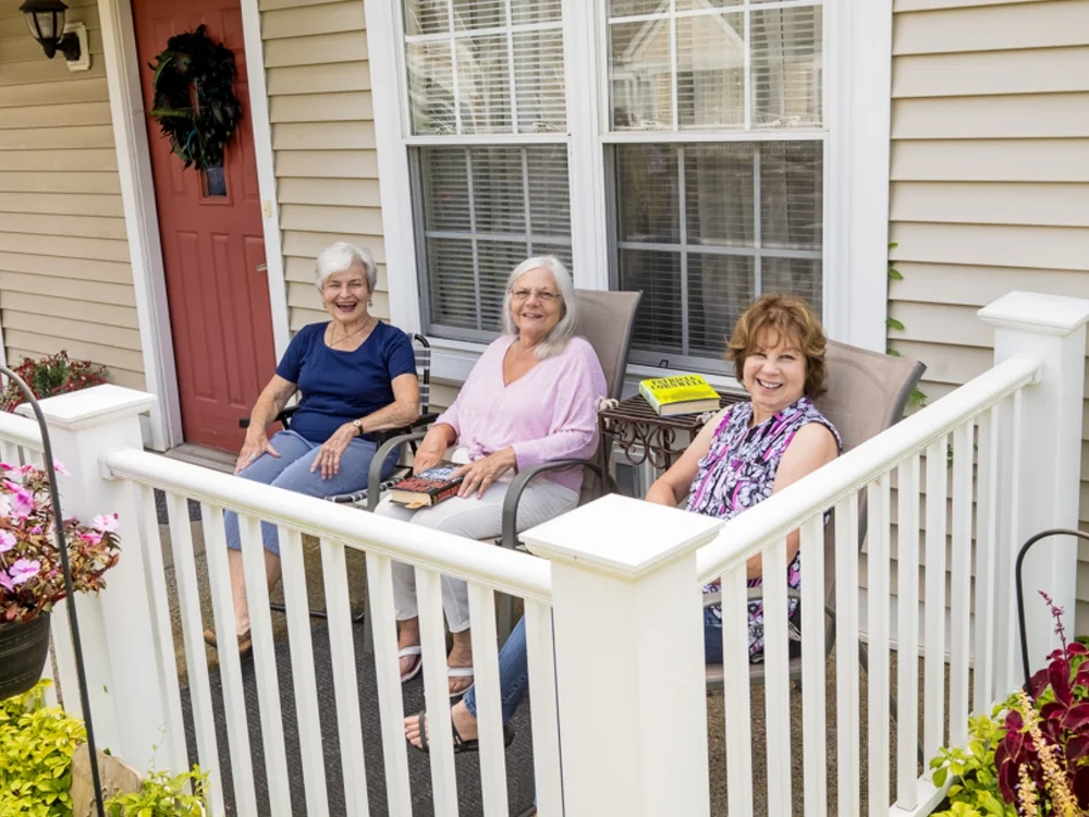 3 women sitting on front porch of a Cedar Ridge apartment building