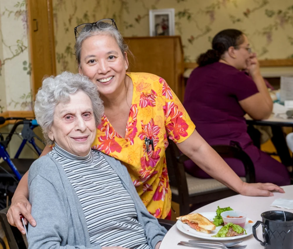 elderly woman and nurse smiling in dining room