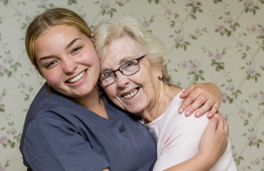 nurse and elderly woman hugging and smiling